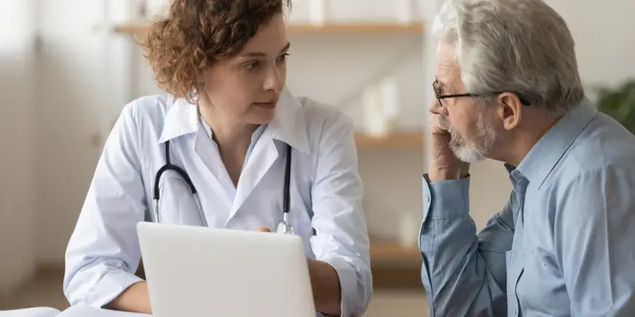 A young doctor consults with a senior patient at a desk